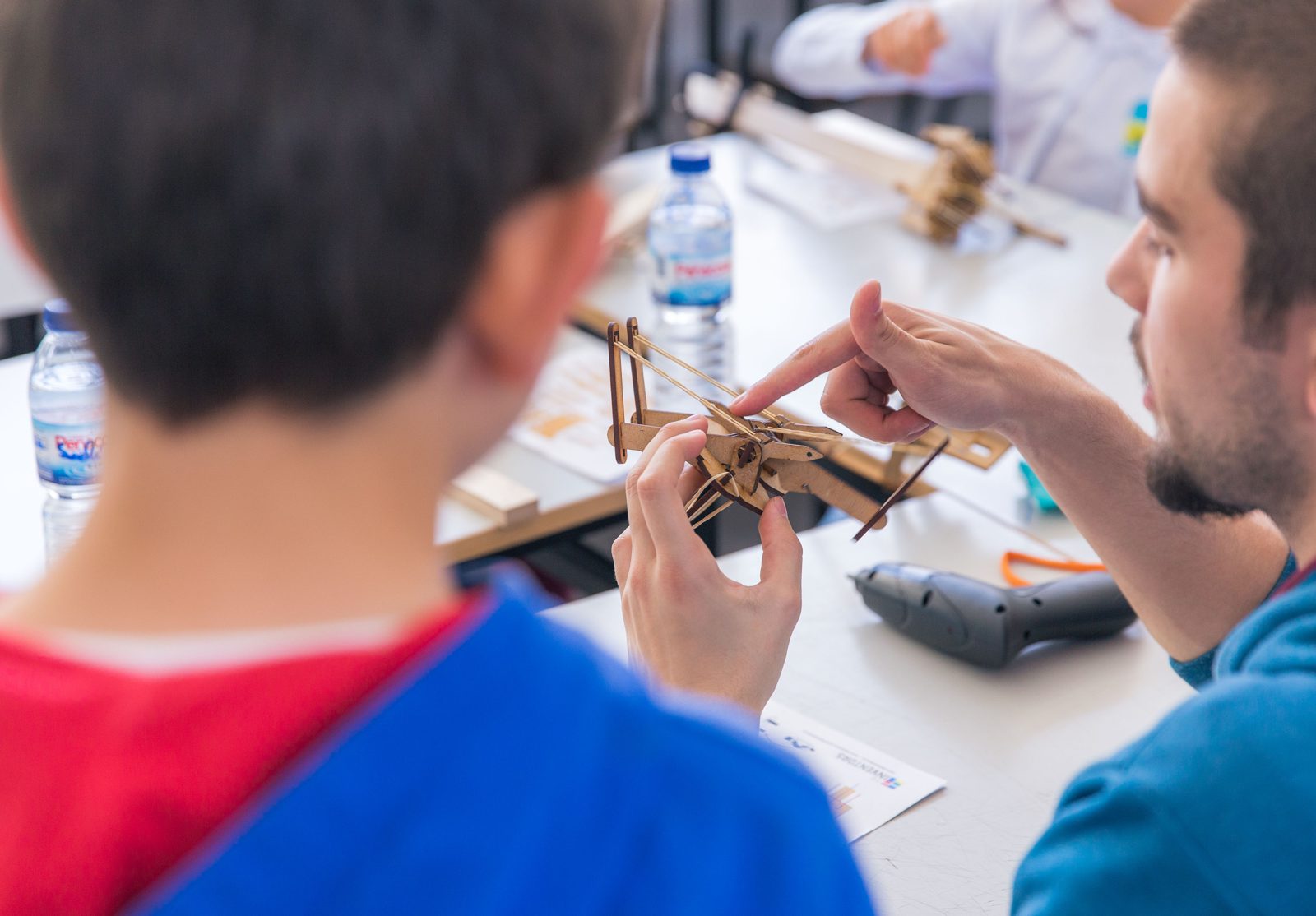 An instructor guides a child building a wooden model