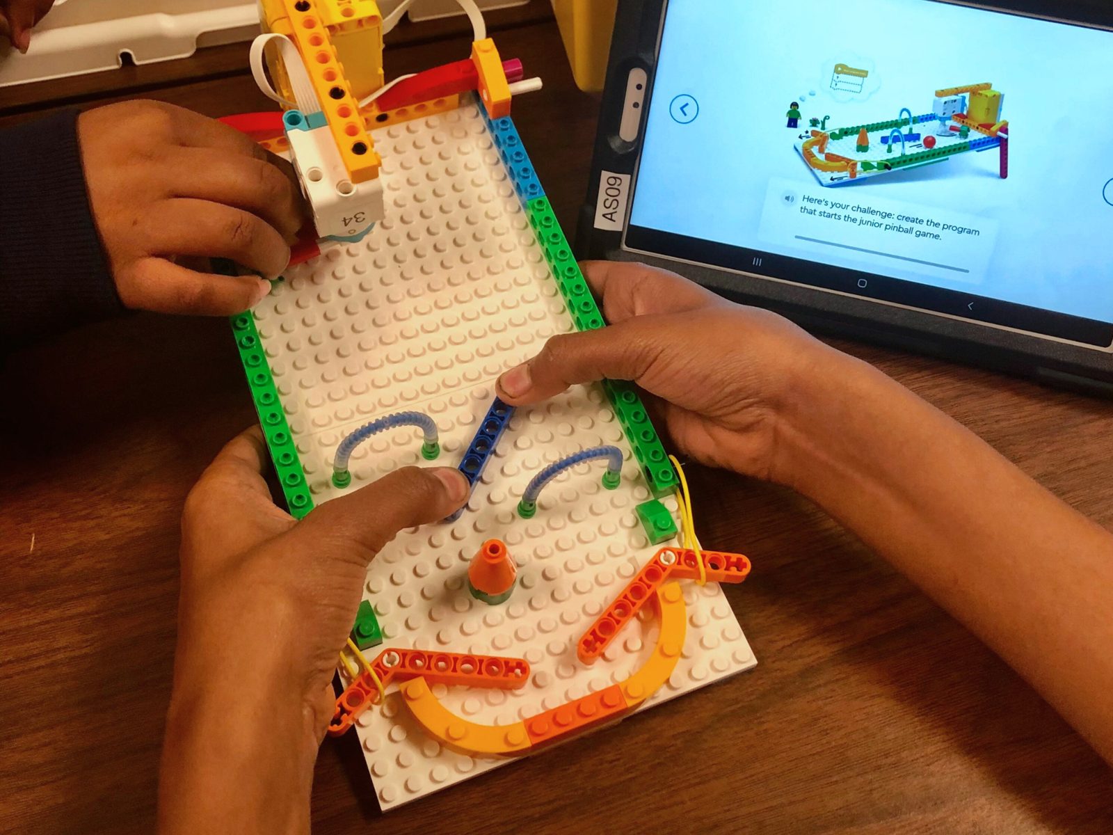 Hands playing a LEGO pinball game built in class